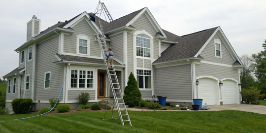Professional painter on a ladder contributes to the average cost of exterior house painting.
